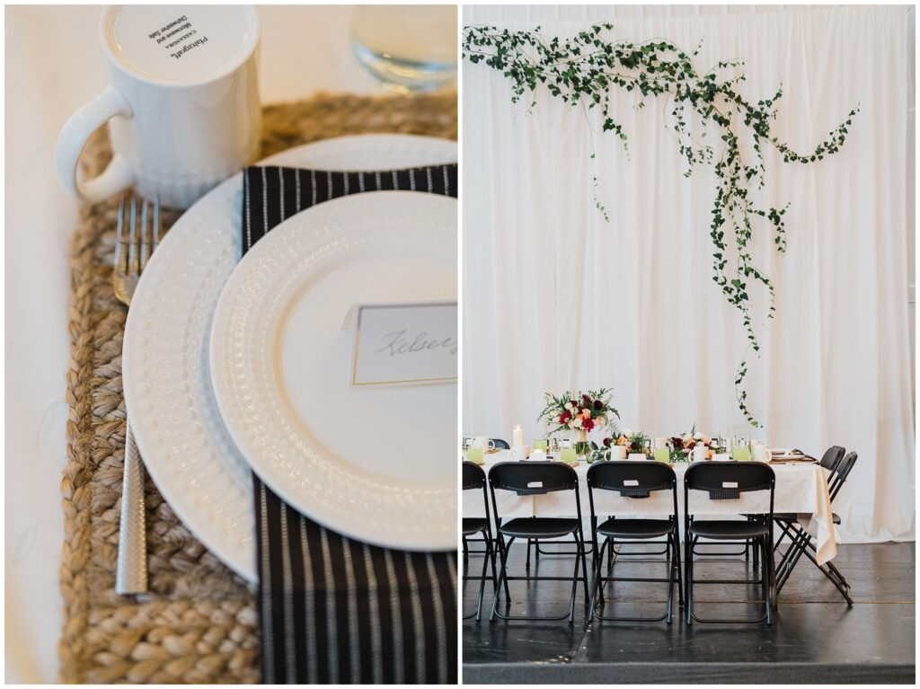 Lovely wedding reception place setting with woven place mat, white plates, and black cloth napkin with white pinstripes and a tablescape with gorgeous multicolored florals under a swag of green ivy